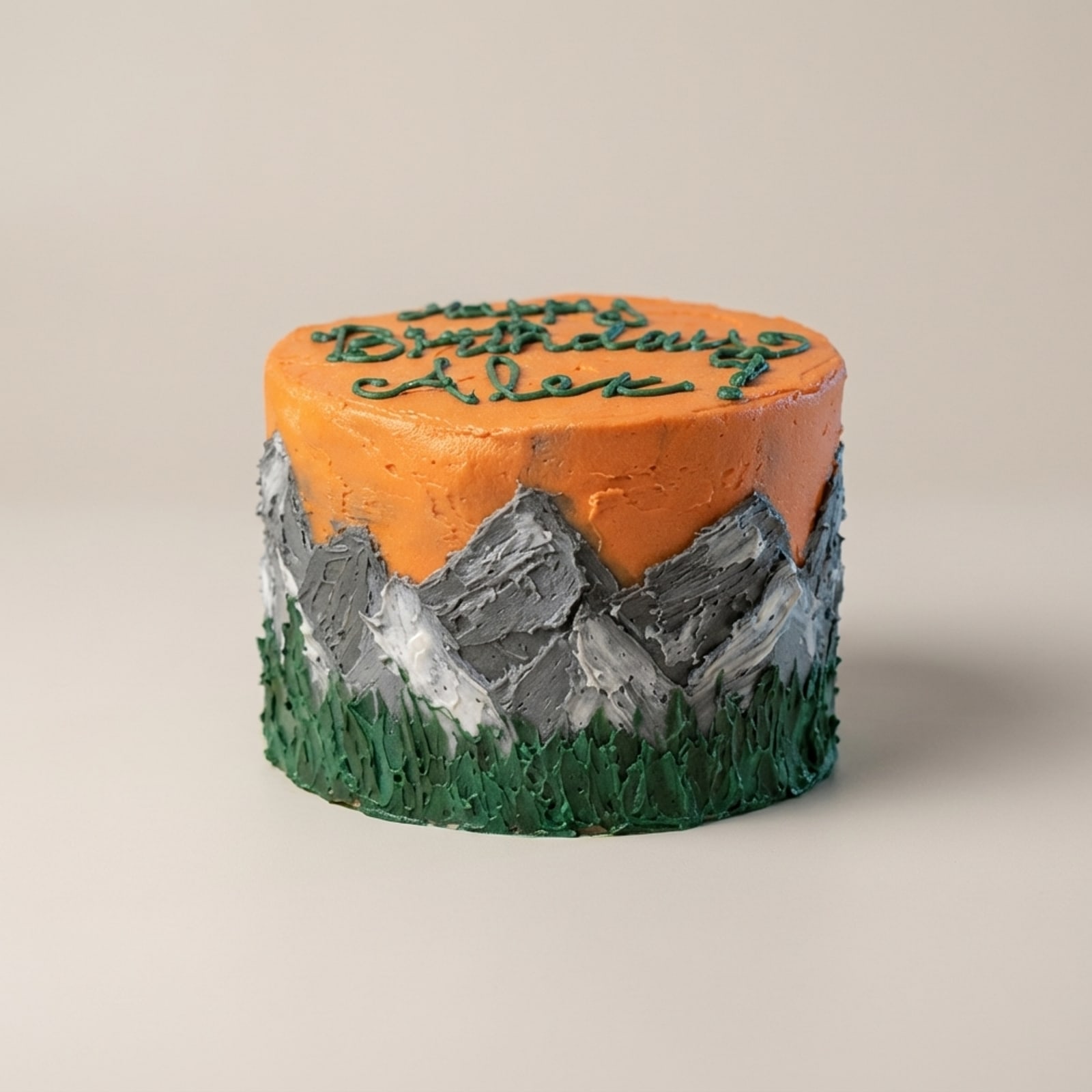 Round birthday cake with orange sky, grey mountain palette-knife buttercream, dark green forest base, and Happy Birthday Alex lettering.